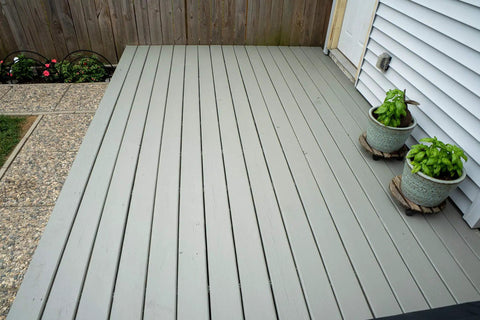 Wood deck with All In One Deck Stain And Sealer With UV Protection In A Solid Gray Finish For Wood Decks Fences And Siding, shown with potted plants