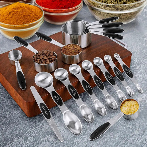16 Piece Measuring Cups And Magnetic Spoons Set In Stainless Steel With 8 Nesting Cups And 7 Double Sided Magnetic Measuring Spoons Plus A Leveler For Dry And Liquid Ingredients A Handy Kitchen Must Have displayed on a wooden board with spices and coffee beans.