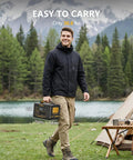 Man carrying Jump1500X Portable Power Station With 828Wh LiFePO4 Battery, Solar Generator by a tent in a scenic campsite
