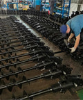 Worker assembling Hydraulic Earth Auger For Mini Excavator Backhoe Post Hole Digger Attachment For Fencing Landscaping And Construction Projects With Pro Grade Torque For Drilling Through Tough Soil.