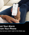 Person testing Smart Carbon Monoxide Detector With Plug In Design And AA Battery Backup, Real Time Notifications, 2.4 GHz Wi Fi Enabled on phone