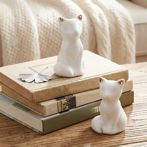 Level Up Your Bathroom Vibe With This Dope Set Of Ceramic Cat Toilet Bolt Covers And Floor Screw Caps Rust Proof Maximalist Accent For Hiding Ugly Base Screws Forever, two white ceramic cat figurines with gold ears on stacked books.