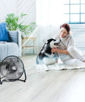 9 Inch Floor Fan With 3 Speed Settings, Portable Metal Design in living room with person and dog, 180 Degree Tilt For A Custom Breeze