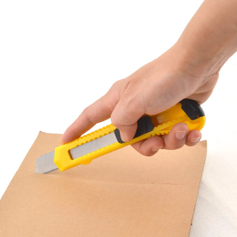 Hand using Heavy Duty Art Knife Plus With 15 Blades For Cutting Crafts And Raw Materials 18mm Utility Knife Set on cardboard