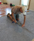 Pro Grade Flooring Underlayment Roll For Laminate Wood And Tile Sound Dampening Padding Compression Resistant Mat For Floating Glue Down Install Covers One Hundred Square Feet being installed by a worker.