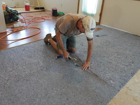Pro Grade Flooring Underlayment Roll For Laminate Wood And Tile Sound Dampening Padding Compression Resistant Mat For Floating Glue Down Install Covers One Hundred Square Feet being installed by a worker.