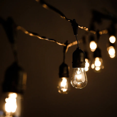 Beefed-Up 100 Foot Outdoor Commercial String Lights With E26 Suspended Sockets, glowing S14 11W bulbs hanging in darkness