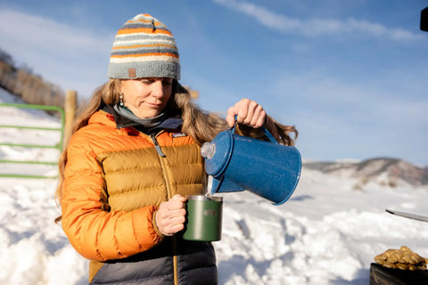 Person pouring coffee from Percolator Coffee Pot For Campfire Brewing, Enamel Camping Kettle For Outdoors in snowy setting