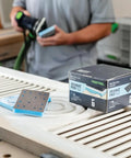 Foam Back Contouring Abrasive Discs With Hook And Loop Mount on table with sanding tool in background, product box visible