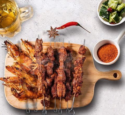 10-inch stainless steel square barbecue skewers, six skewers laid on a wooden board with grilled kebabs
