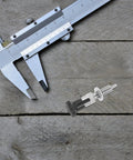 Heavy Duty Stainless Steel Indexing Plunger With Knurled Grip Handle shown with caliper on wooden surface for precise measurement.