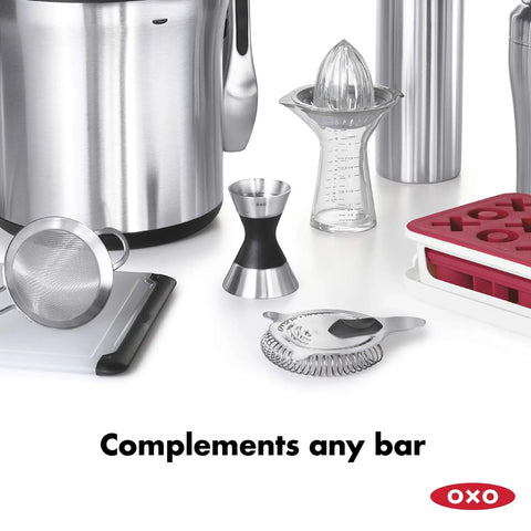 Stainless Steel Two Sided Jigger With Flip Measurements on a bar counter with other kitchen tools