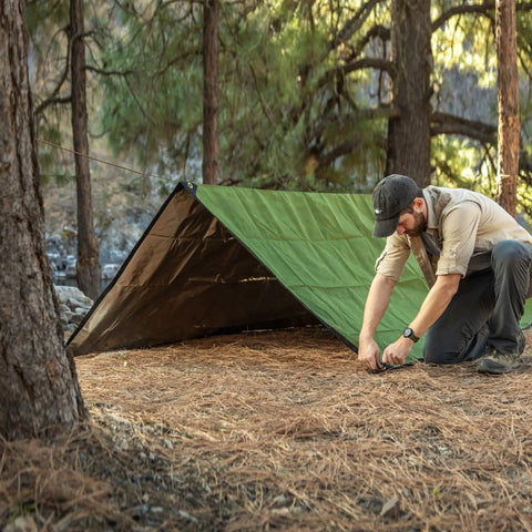 Tough As Nails Heavy Duty Survival Blanket With Reflective Thermal Layer For Camping And Outdoor Gear Waterproof Tarp Or Shelter 8.5 Ft By 12 Ft Olive Green All Weather Ready set up in forest