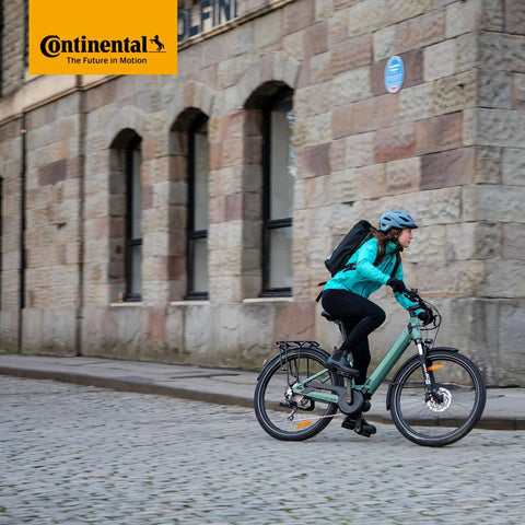 Cyclist on a city street using Tour 28 Inner Tubes For 700C Bikes That Fit 32 To 47Mm Wide Tires With 40Mm Schrader Valve and levers