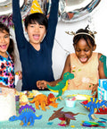 Children celebrating with Fun Wooden Dinosaur Craft Kit For Kids Aged 4 To 8 3D DIY Painting Set With Six Dinosaur Figures at table.