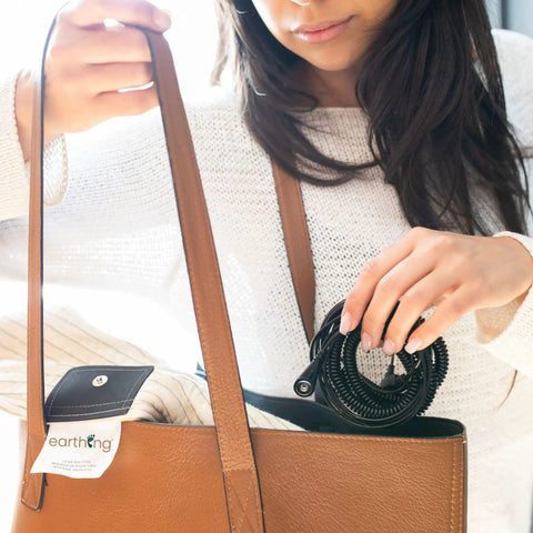 Woman placing Grounding Blanket Throw Kit With Ground Therapy Coil Cord, 44 By 68 Inch, in a brown bag.