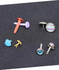 Assorted colorful metal brads with split pins on a black surface, part of 110 PCS Colorful Metal Brads Fasteners For Scrapbooking And Cardmaking.