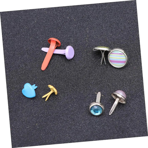 Assorted colorful metal brads with split pins on a black surface, part of 110 PCS Colorful Metal Brads Fasteners For Scrapbooking And Cardmaking.