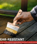 Hand using large brush from 3-Piece Deck Stain Brush Set for Limewash and Wood Stain on a wooden deck