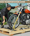 Man securing motorcycle with straps and Four Pack E Track Wheel Chocks For Enclosed Trailers And Garages on wooden platform.