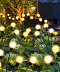 Upgraded Solar Firefly Lights 4 Pack Outdoor Waterproof 8 LED Starburst Swaying Lights illuminating a garden at night.
