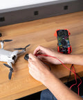 Person using Auto-Ranging Digital Multimeter For Automotive And Home Electrical Troubleshooting UL Certified on drone battery.