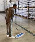 Man using Top Shelf 24 Inch Cotton Dust Mop Kit With Heavy Duty Aluminum Handle For Dead Easy Floor Sweeping And Hardwood Dust Pick Up In Commercial Home Or Business Spaces in a warehouse.
