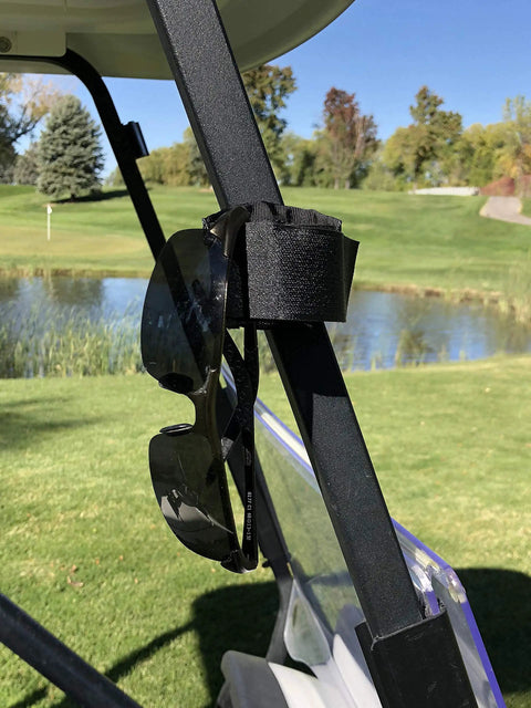 Black Magnetic Rangefinder Strap with sunglasses attached on golf cart rail for hands-free access on the course.