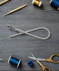 Foldable Drawstring Threaders Kit with Latch Hook 20 pieces on wooden table with scissors, blue threads, and crochet hook.