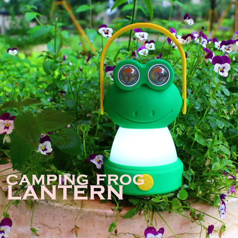 Green frog-shaped LED lantern surrounded by flowers, resembling Owl Themed Kid Friendly LED Lantern And Headlamp Set for camping.