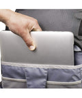 Person placing a laptop into BackLight Elite 45L Camera Daypack For DSLR And Mirrorless Gear, Rugged Grey, large compartment visible.