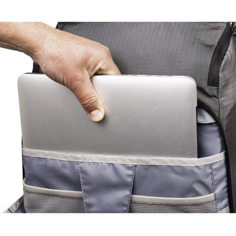 Person placing a laptop into BackLight Elite 45L Camera Daypack For DSLR And Mirrorless Gear, Rugged Grey, large compartment visible.