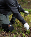 Person wearing Heavy Duty Work Knee Pads With Soft Gel Core And Durable EVA Foam Padding, removing weeds in a garden.