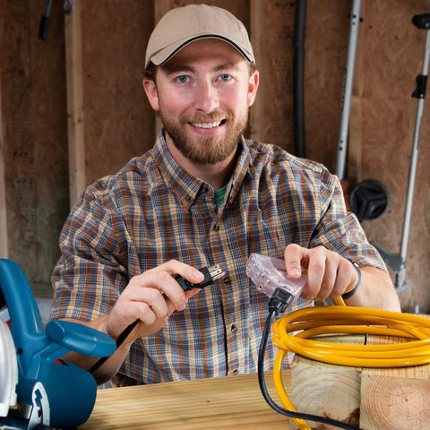Man connecting 2 Ft Outdoor Extension Cord Waterproof Heavy Duty 12 Gauge With Multiple Outlets Lighted Grounded For Tools, Lights, Generators And Outdoor Power Solutions on a workbench.