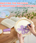 Easy Peasy Beginner Punch Needle Kit For Adults With All Tools And Materials Easy To Follow Instructions And Videos Water Soluble Pattern On Linen Axolotl And Octopus Design No Fuss Embroidery Starter For Relaxation And Skill Building shown with octopus pattern in a hoop, book, threads, and a coffee cup on a table.