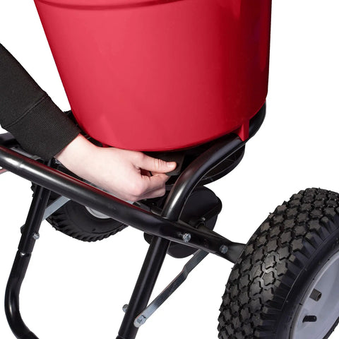 Adjusting drop rate on Heavy Duty 50 Lb Broadcast Fertilizer Spreader for Lawns with large 13 inch pneumatic stud tires.
