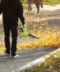Person using Cordless Leaf Blower With Dual Batteries And Charger 130 MPH 180 CFM High Speed Air Lightweight 20V Electric Handheld Blower For Quick Lawn Cleanups Patio Garden And Home Use on a path.