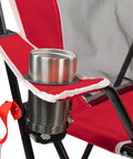 Comfort Pro Rocker Camping Chair With Drink Holder detail showing cup slot, red fabric, black frame, and mesh pocket.