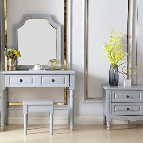 Elegant gray vanity set with mirror, stool, and drawers with decorative accents, set against a white wall.