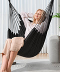 Woman relaxing in hammock chair hanging rope swing for indoor outdoor use chill cozy and durable supports up to 500 lbs two cushions included dark grey
