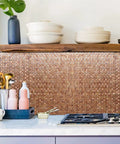Self Adhesive Aluminum Mosaic Backsplash Tiles Five Sheet Set for Kitchen Walls and More Peel and Stick Silver Stainless Steel Look with Textured Metal Finish Easy DIY Installation Modern Home Decor, installed in a kitchen, showing a neat pattern above a countertop with utensils and pot.