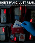 Open red 556-piece premium large first aid kit with labeled compartments and a blue-gloved hand placing a gauze pad.