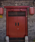 Traditional double red door with metal handles and decorative Chinese lanterns