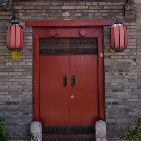 Traditional double red door with metal handles and decorative Chinese lanterns