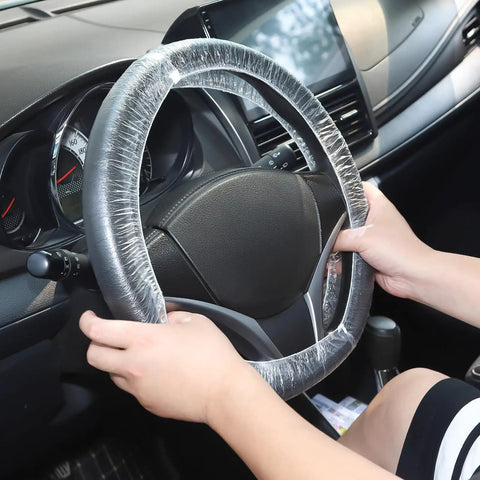 Hands placing a 100 Pack Disposable Steering Wheel Cover With Elastic Fit on a car wheel for spill protection and clean rides.
