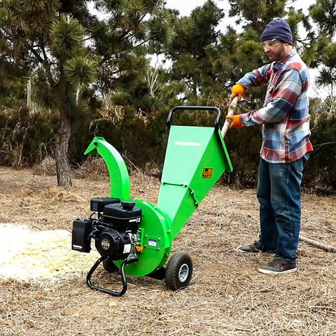 Man using Beast Mode Gas Powered Wood Chipper Shredder Mulcher With 20 To 1 Reduction Ratio in a yard to mulch branches.