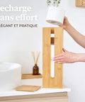 Person placing roll in Bamboo Toilet Paper Storage Holder With Lid On A Sturdy Bamboo Base, Space Saving Roll Dispenser