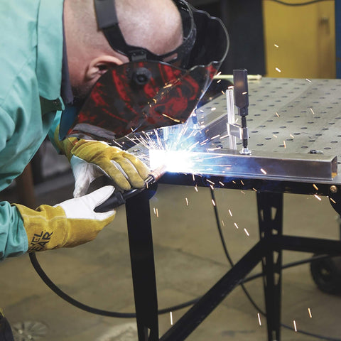 Person welding metal using 4 Piece Welding Table Clamp Kit With Lightweight Aluminum Frame And ABS Handle, black metallic finish, on table