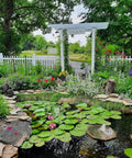 Lush garden pond with lily pads and a decorative white archway surrounded by flowers and greenery