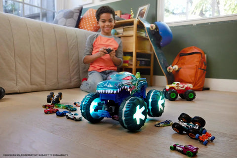 Child playing with Mega-Wrex 1:15 Scale RC Monster Truck With Lights And Sounds, surrounded by toy cars on a wooden floor